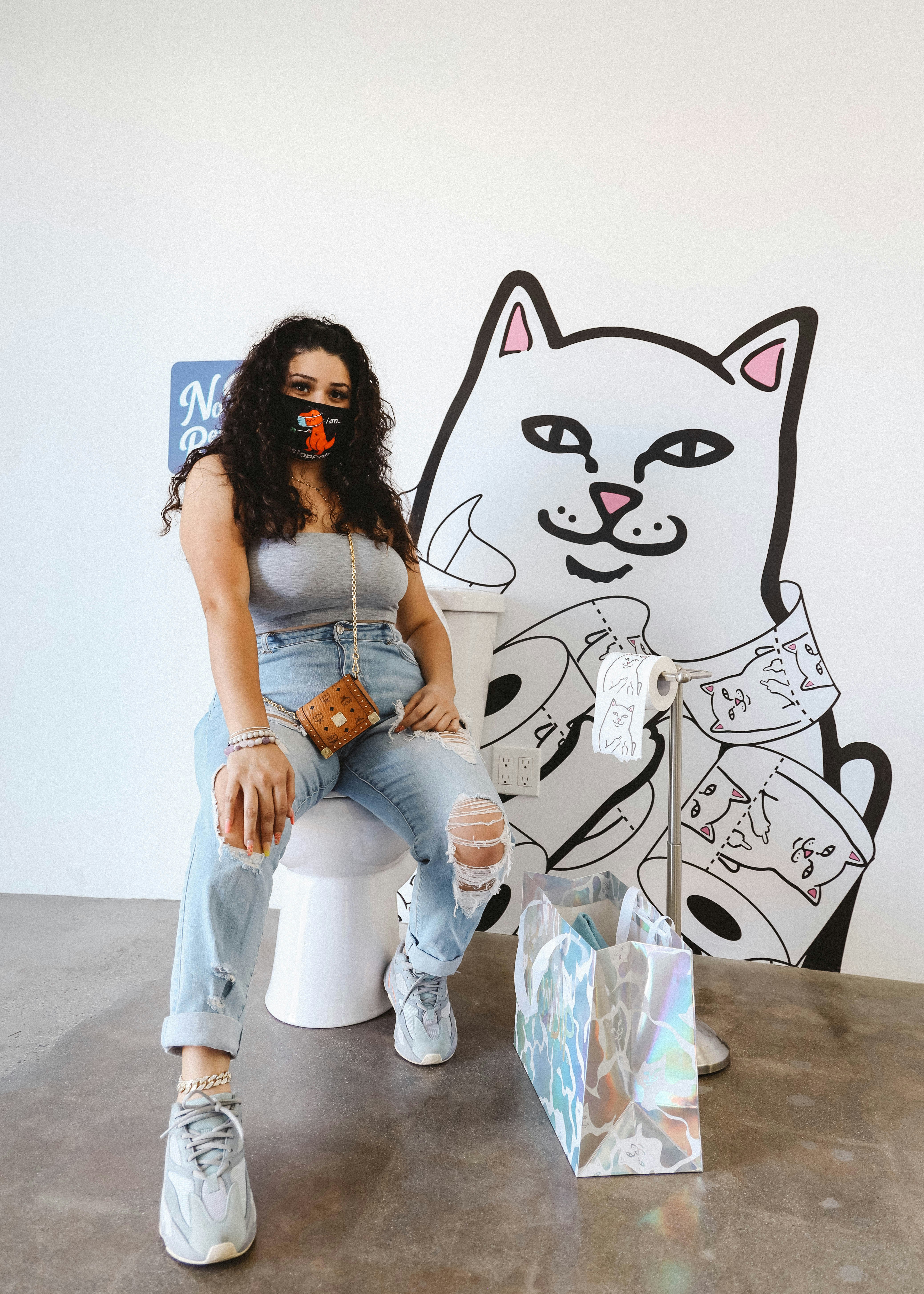 woman in white tank top and blue denim jeans sitting on white plastic seat